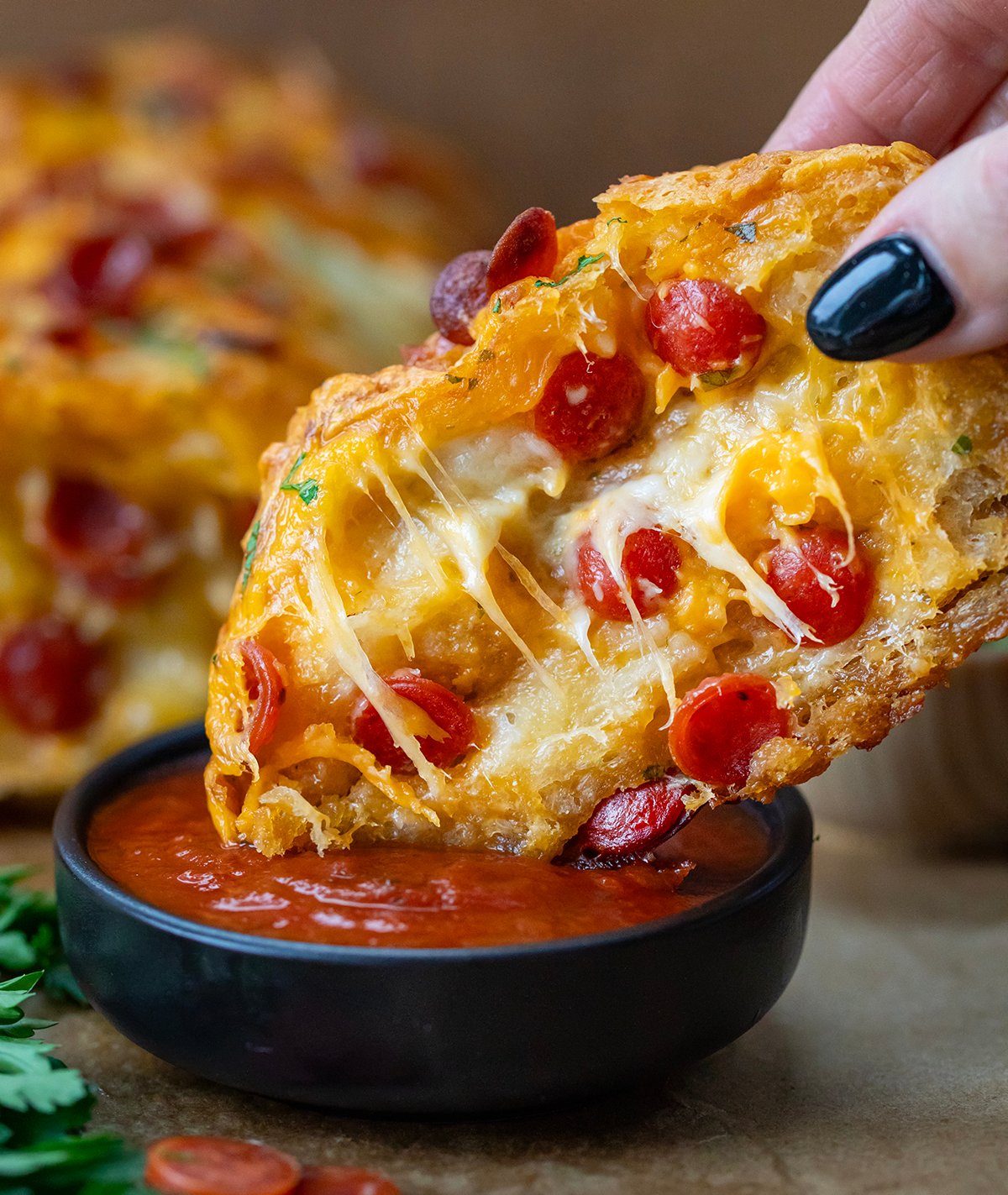 Piece of Pepperoni Pull Apart Bread being dipped into sauce.