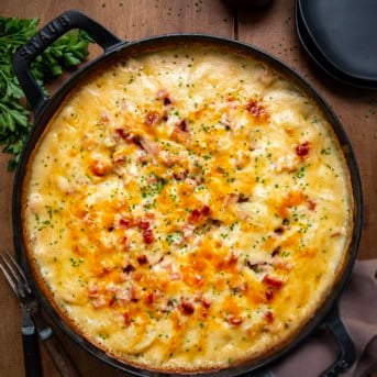 Skillet of Ranch Scalloped Potatoes and Ham on a wooden table from overhead.