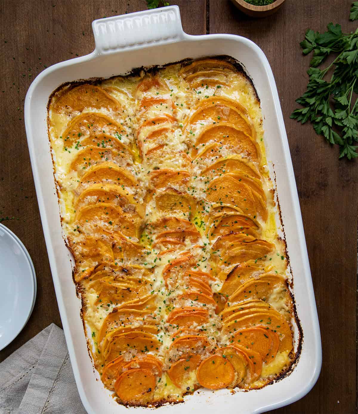 Scalloped Sweet Potatoes in a pan on a wooden table from overhead.