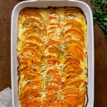 Scalloped Sweet Potatoes in a pan on a wooden table from overhead.