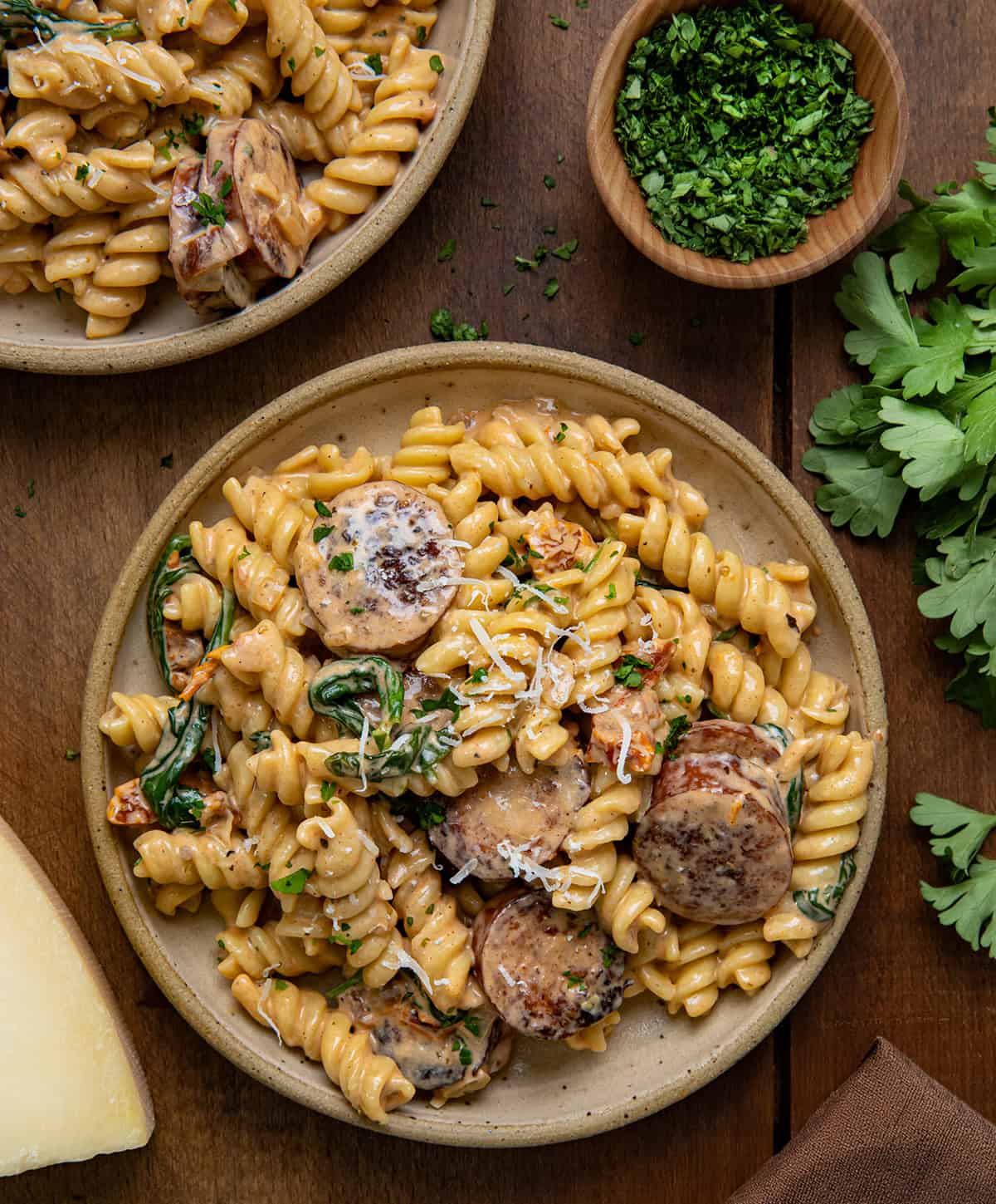 Plates of Creamy Andouille Sausage Pasta on a wooden table from overhead.