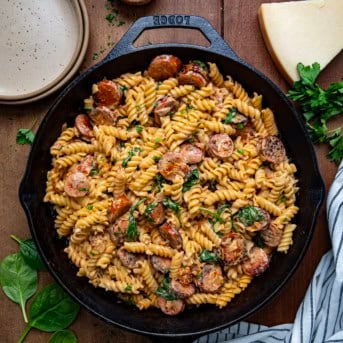 Skillet of Creamy Andouille Sausage Pasta on a wooden table from overhead.