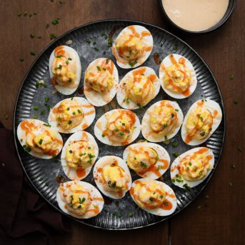 Plate of Bang Bang Deviled Eggs on a wooden table from overhead.