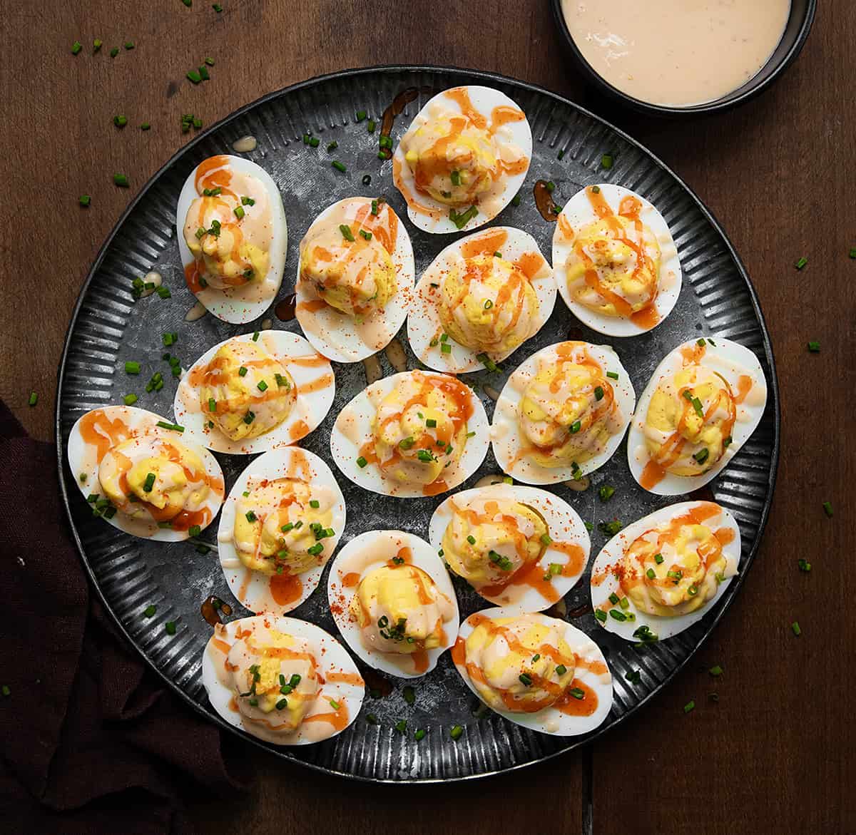 Plate of Bang Bang Deviled Eggs on a wooden table from overhead.