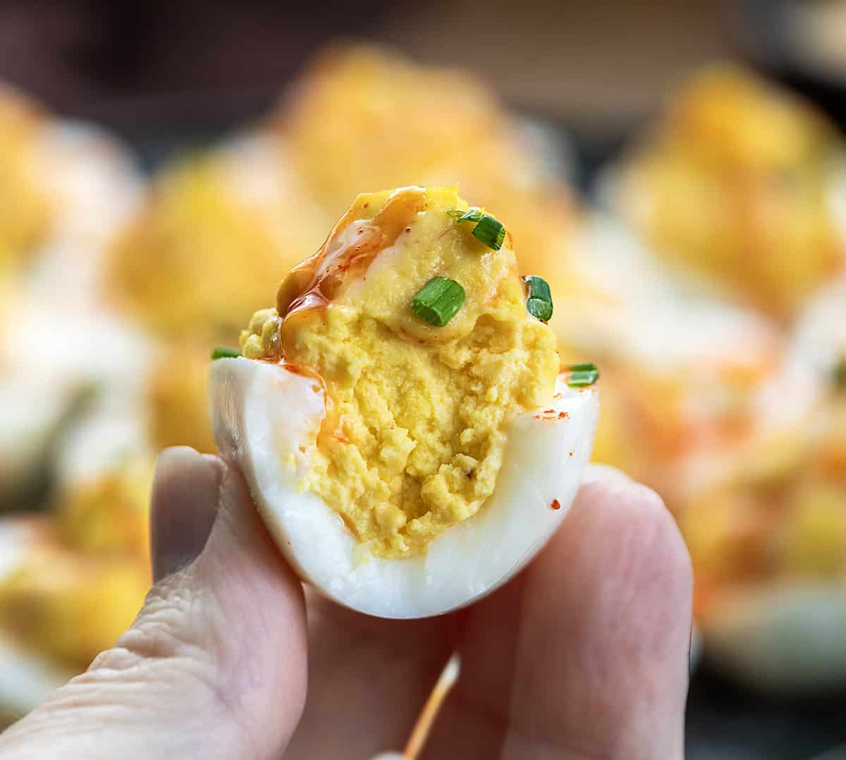 Hand holding a bit into Bang Bang Deviled Egg.