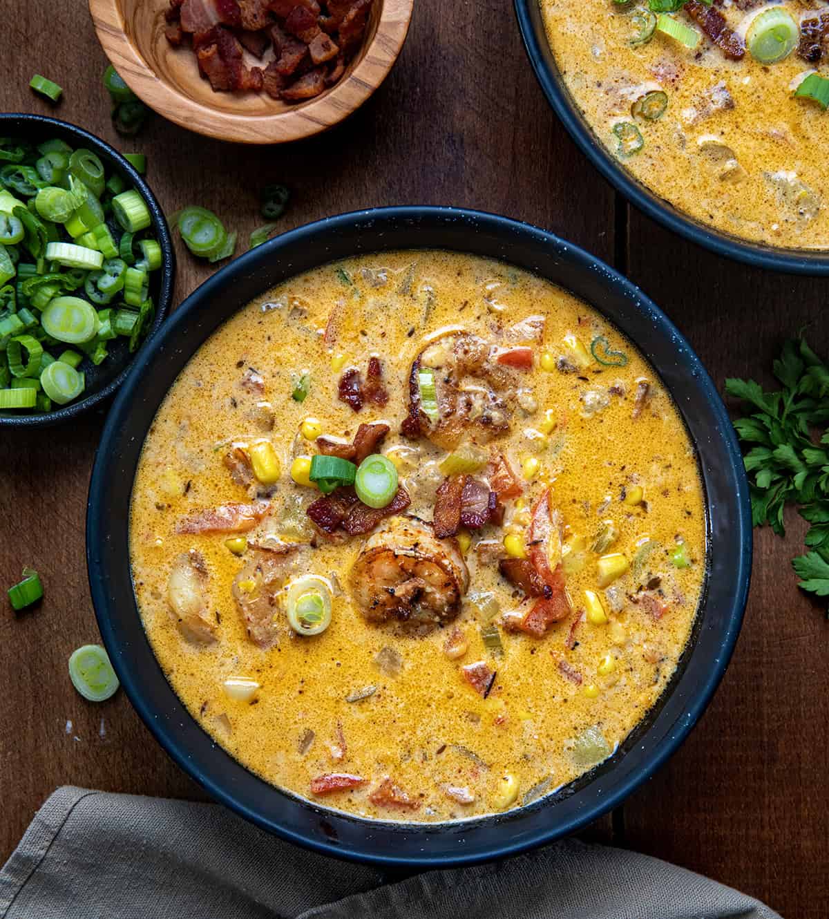 Bowls of Blackened Shrimp and Corn Chowder on a wooden table from overhead.