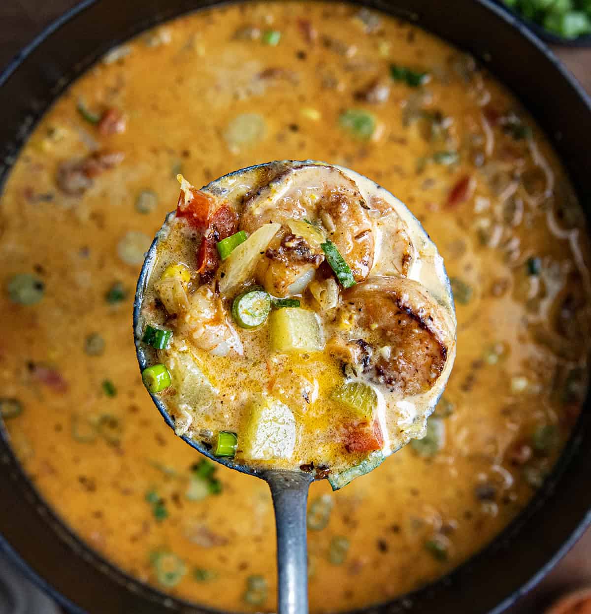 Scoop of Blackened Shrimp and Corn Chowder held over the pot.