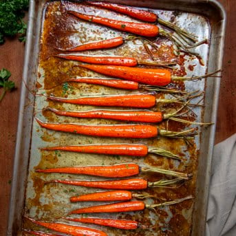 Sheet pan of Bourbon Glazed Carrots on a wooden table from overhead.