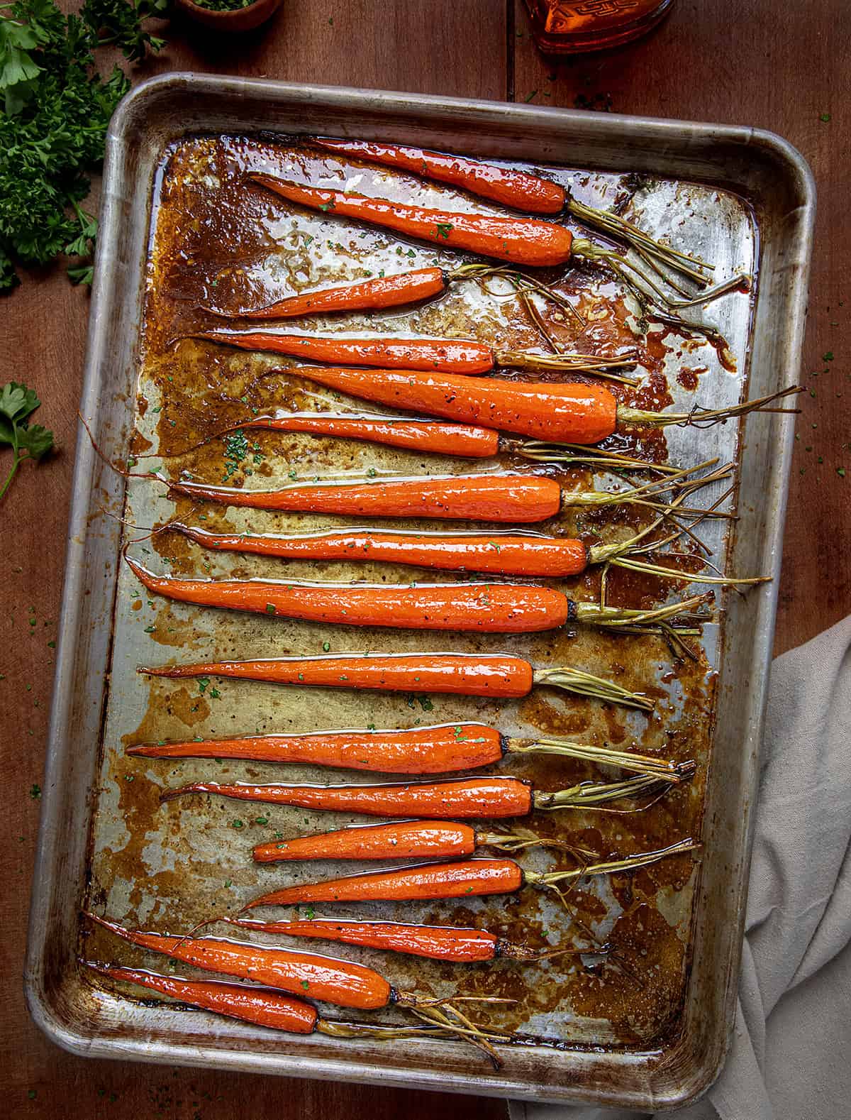 Sheet pan of Bourbon Glazed Carrots on a wooden table from overhead.