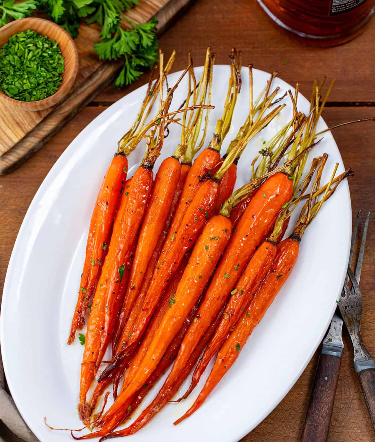 White plate with Bourbon Glazed Carrots on it on a wooden table.