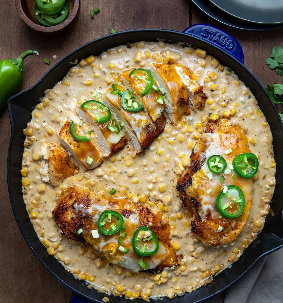 Skillet of Cheesy Jalapeno Stuffed Chicken with one chicken breast cut up on a wooden table from overhead.