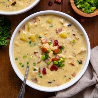 Bowls of Chicken Bacon Potato Soup on a wooden table from overhead.