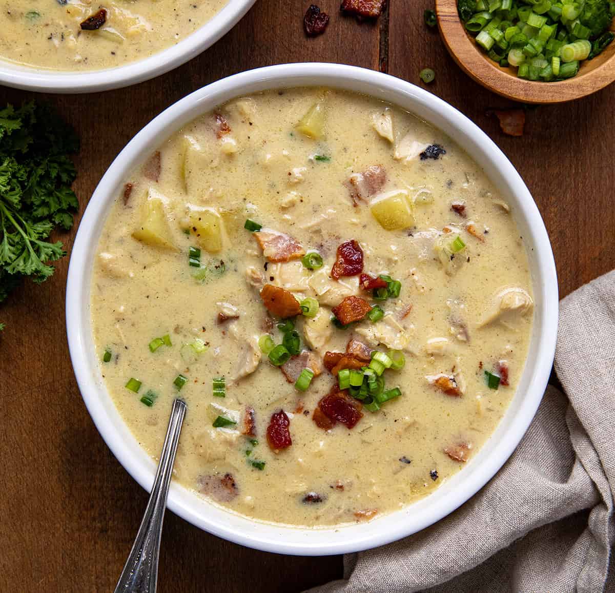 Bowls of Chicken Bacon Potato Soup on a wooden table from overhead.