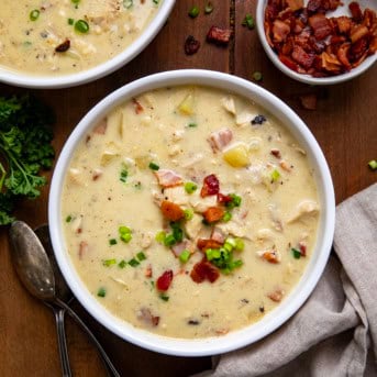 Bowls of Chicken Bacon Potato Soup on a wooden table from overhead.