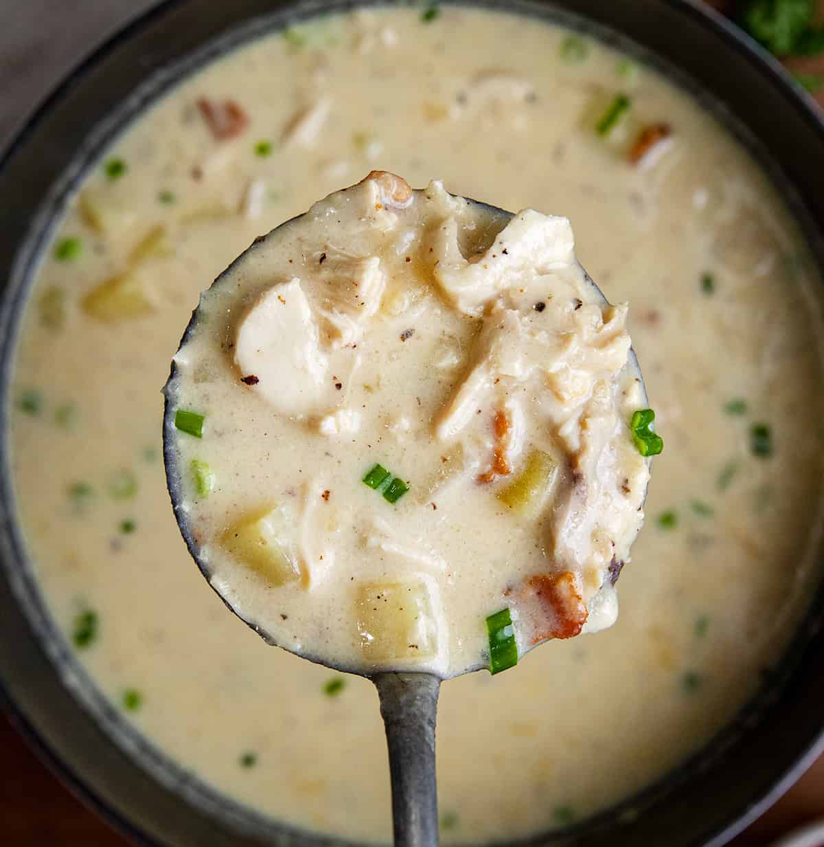 Ladle full of Chicken Bacon Potato Soup held over the top of the pot.