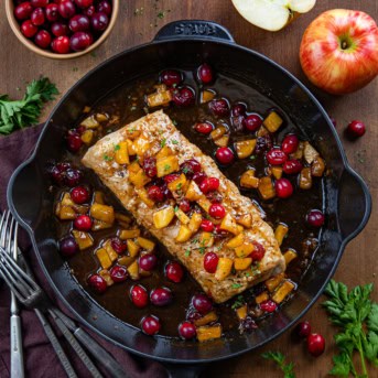 Whole Cranberry Apple Pork Tenderloin in a skillet on a wooden table from overhead.