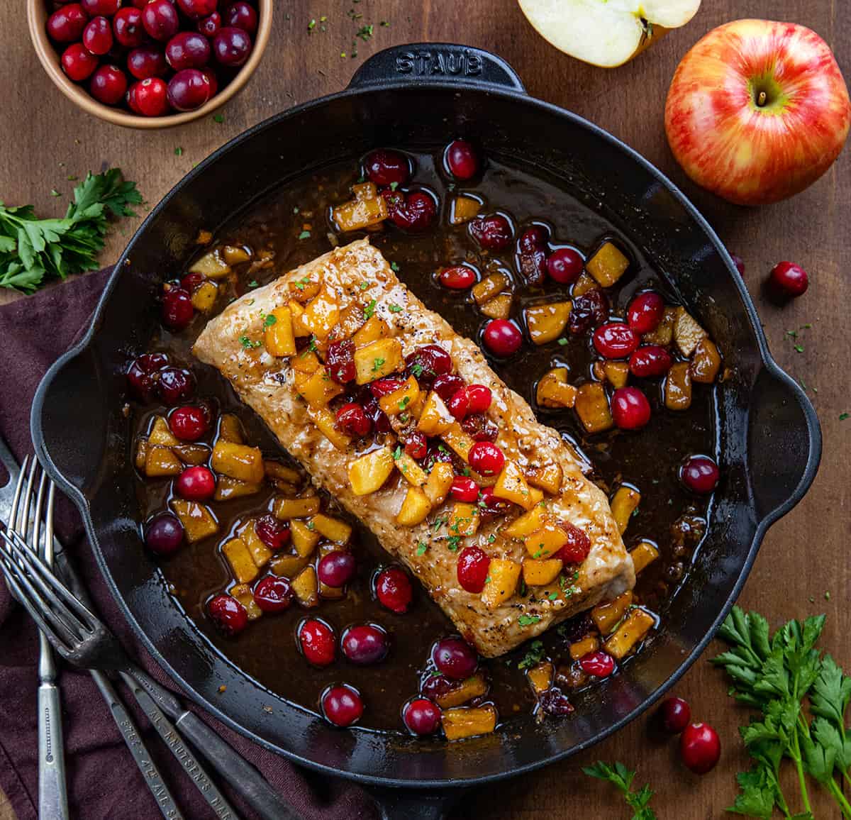 Whole Cranberry Apple Pork Tenderloin in a skillet on a wooden table from overhead. 
