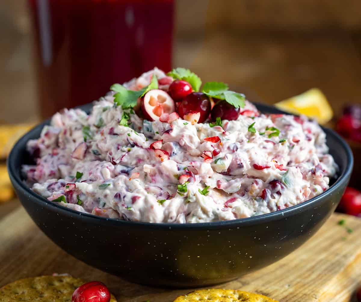 Black bowl of Creamy Cranberry Jalapeño Dip on a wooden table.