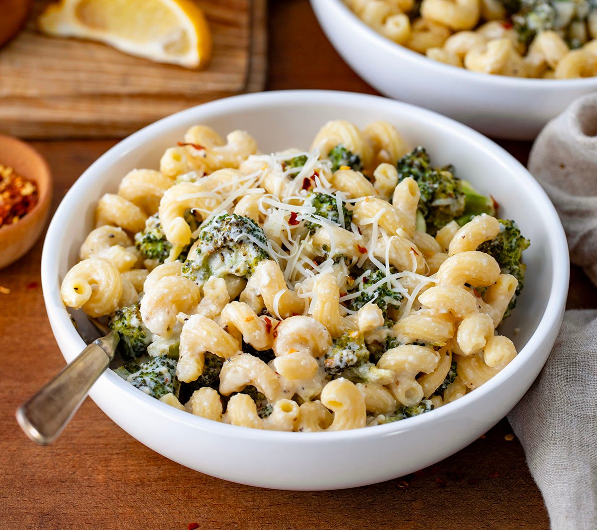 White bowls of Creamy Ricotta Pasta with Roasted Broccoli on a wooden table.