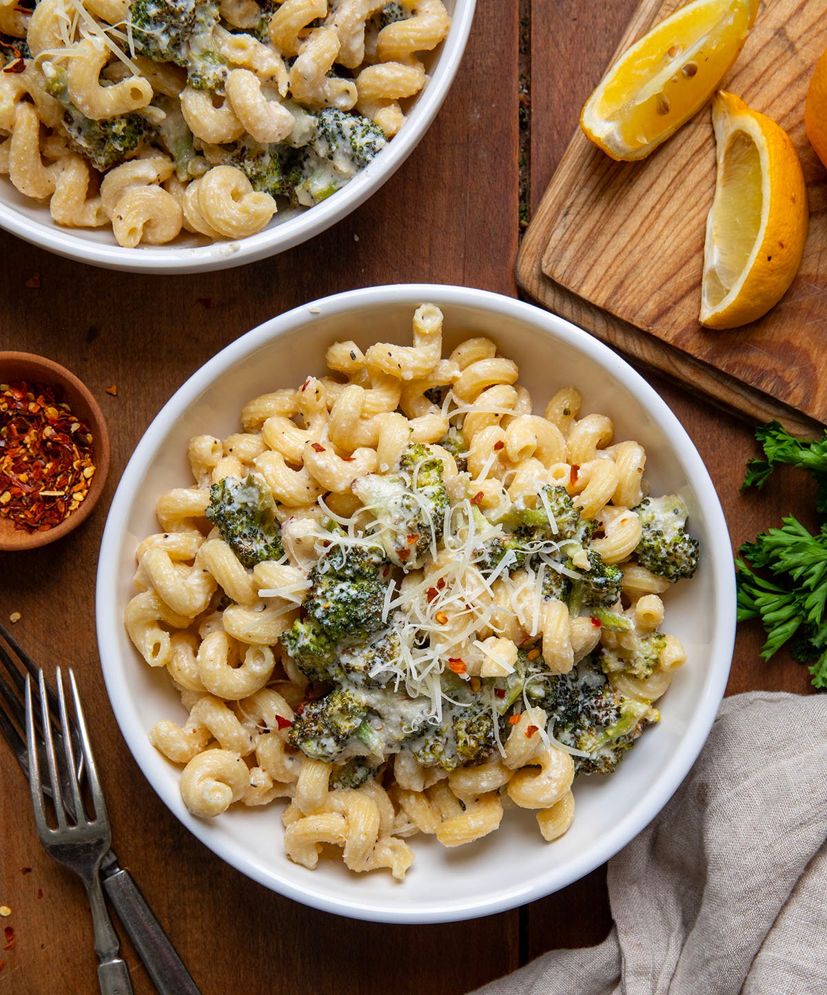 White bowls of Creamy Ricotta Pasta with Roasted Broccoli on a wooden table from overhead.