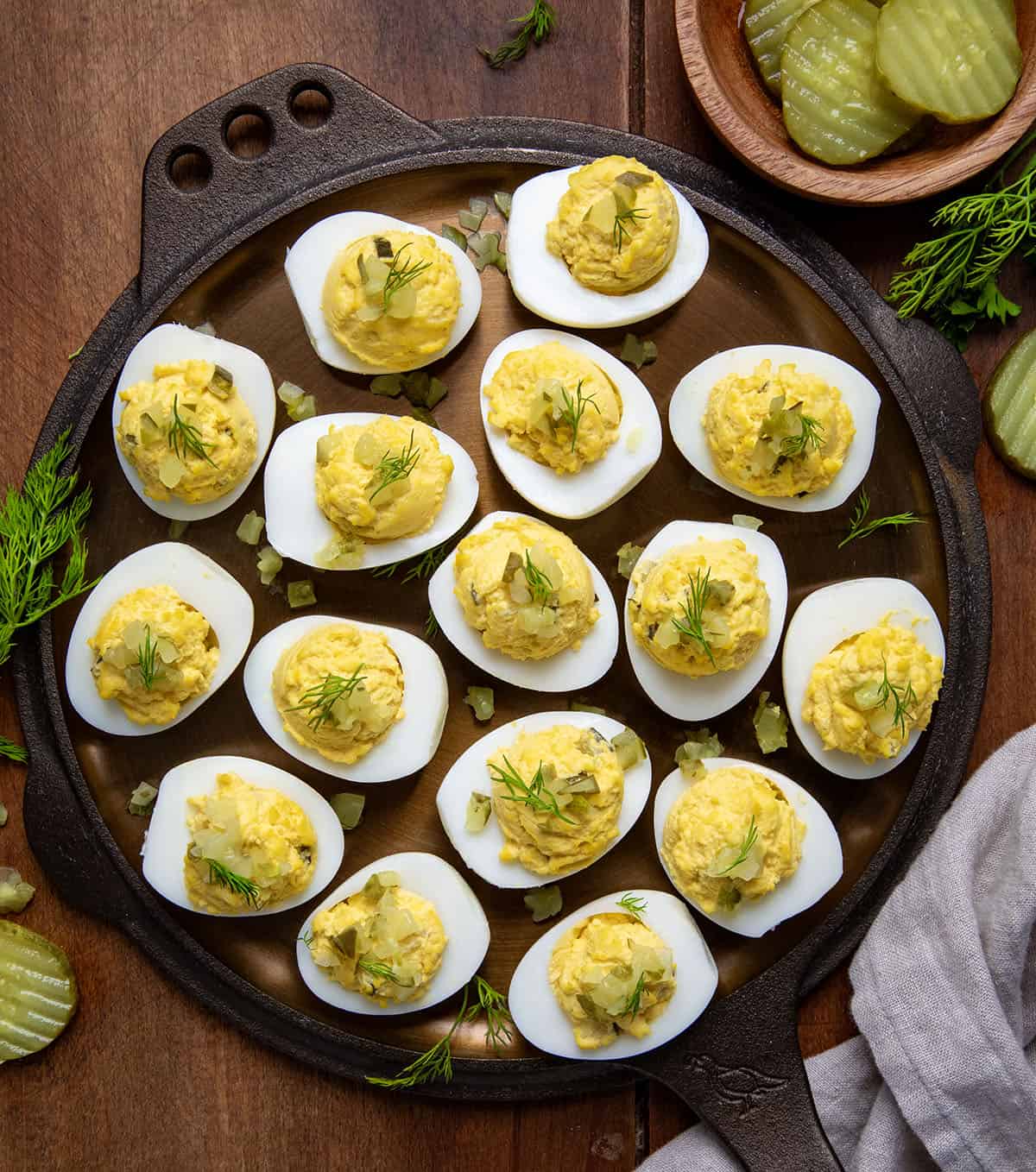 Dill Pickle Deviled Eggs on a wooden table from overhead with dill pickles and fresh dill around. 