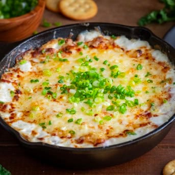 Skillet of Hot Ham and Cheese Dip on a wooden table.