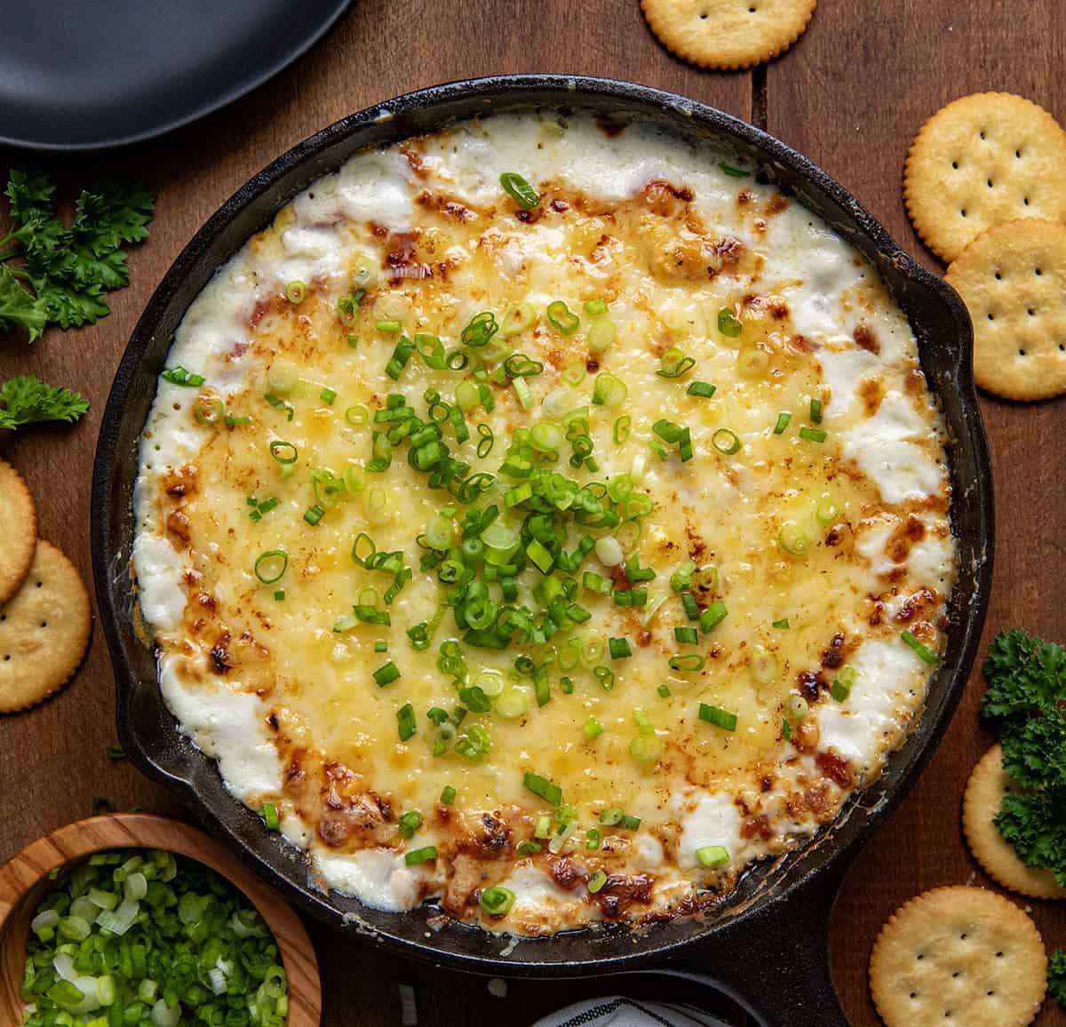 Skillet of Hot Ham and Cheese Dip on a wooden table from overhead.