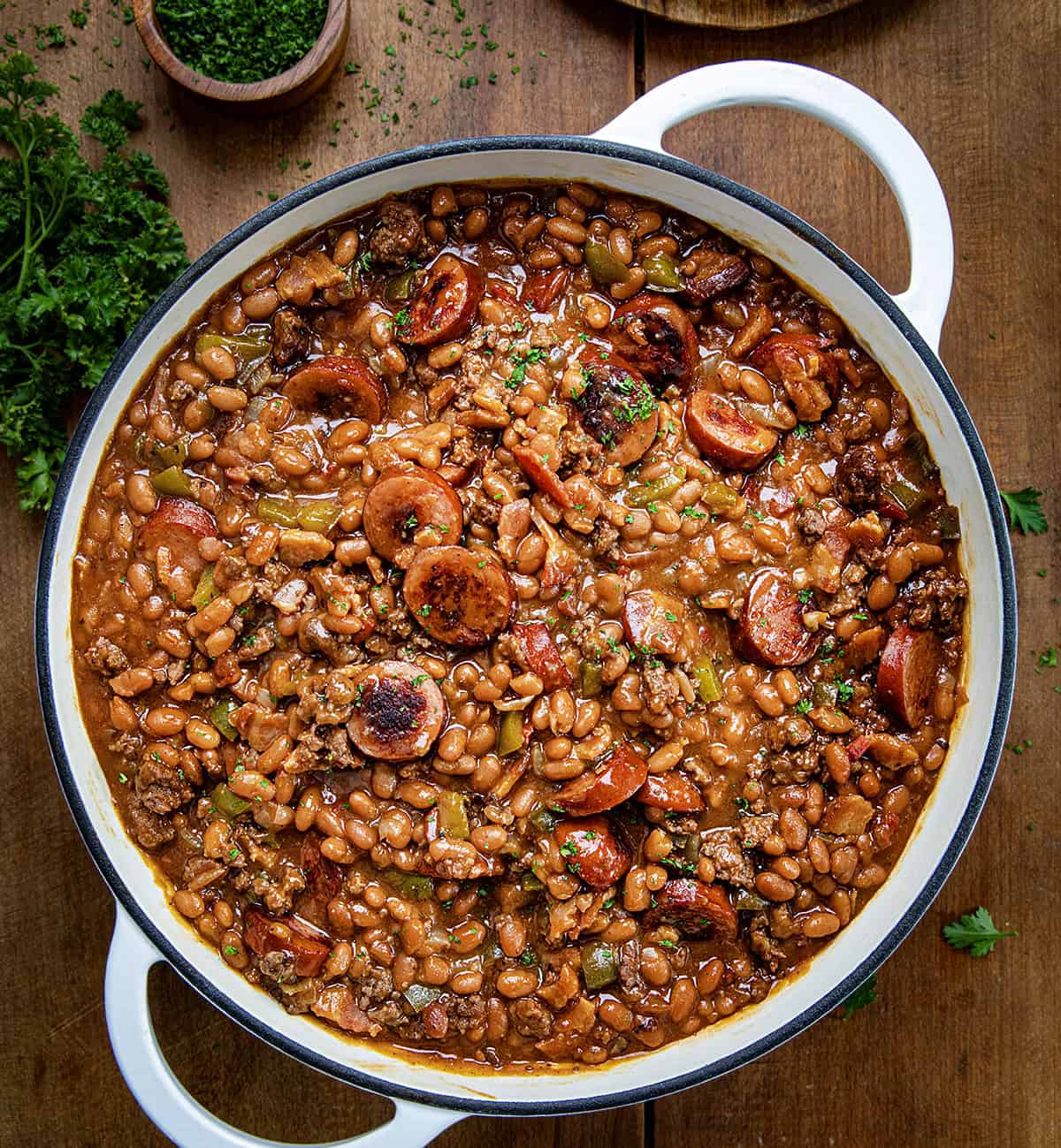 Pot of Kielbasa Cowboy Beans on a wooden table from overhead.