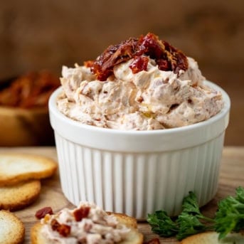 Bowl of Sun-Dried Tomato Spread on a cutting board.