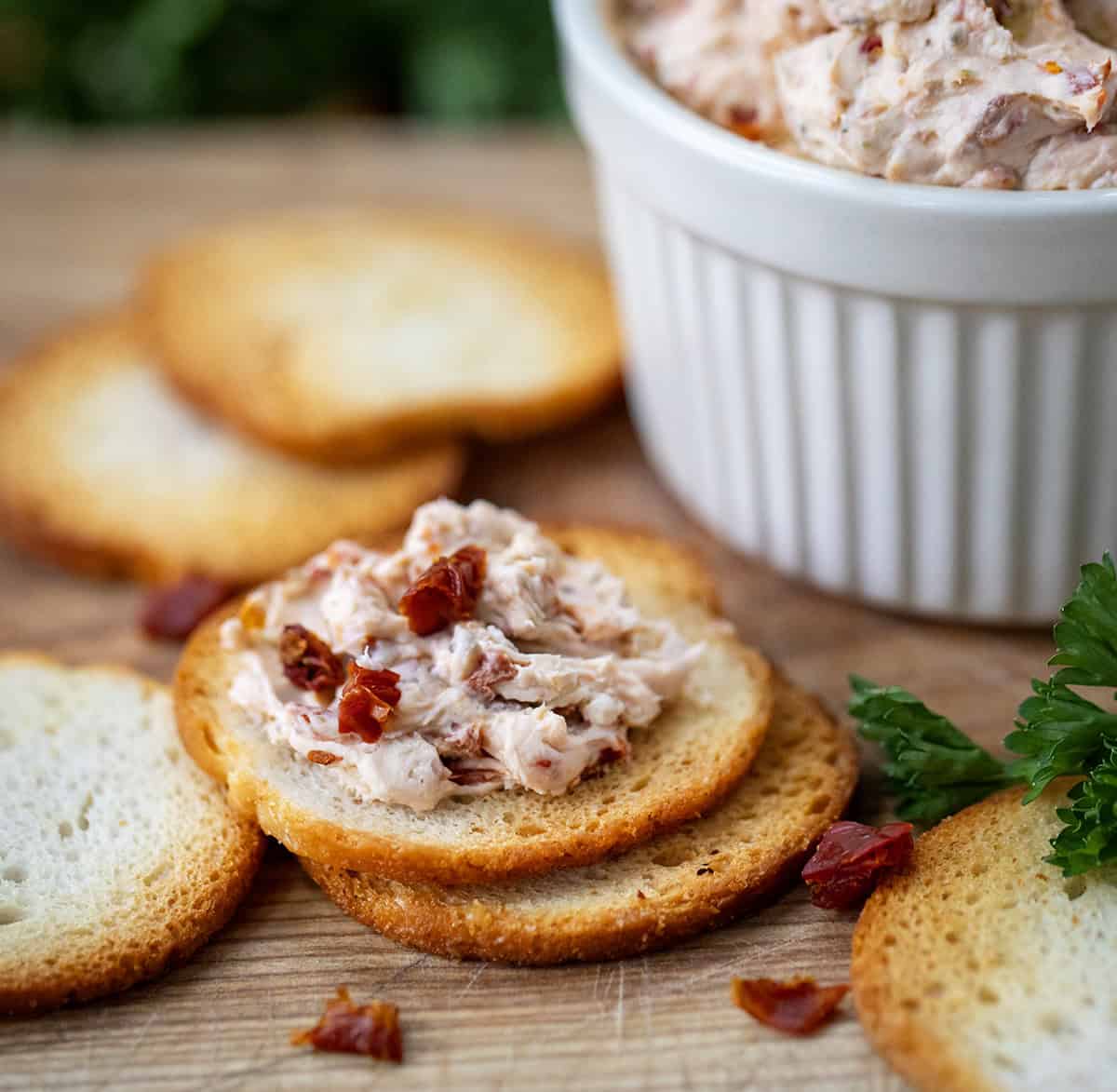 Sun-Dried Tomato Dip on a cracker on a wooden table.