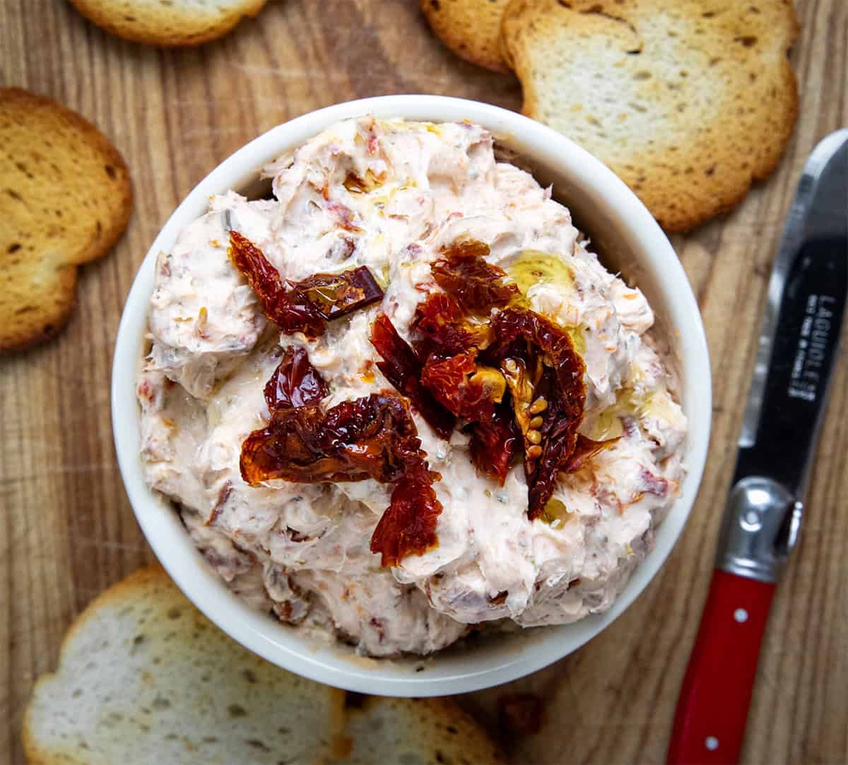 Sun-Dried Tomato Dip on a wooden table from overhead.