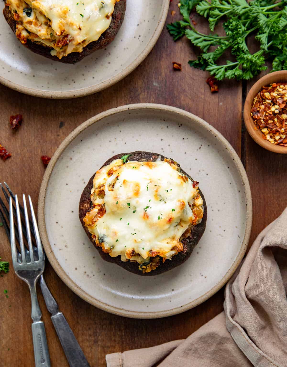 Tuscan Stuffed Mushroom Caps on plates on a wooden table from overhead.