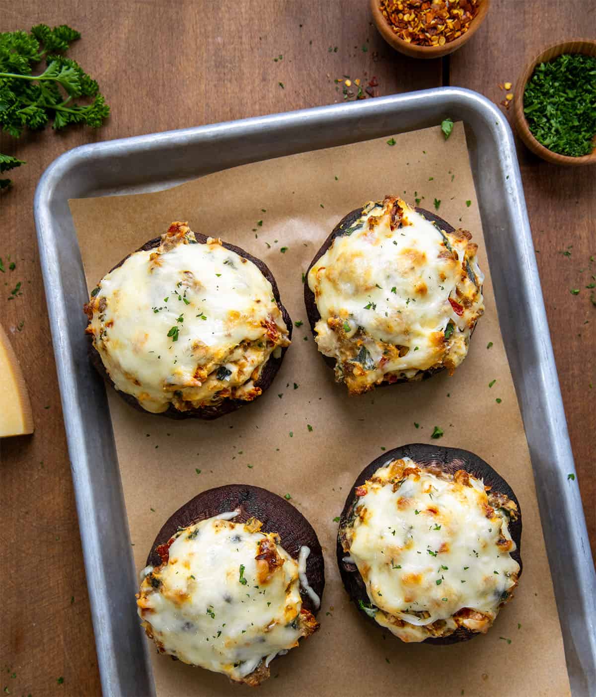 Tuscan Stuffed Mushroom Caps on a sheet pan on a wooden table from overhead.