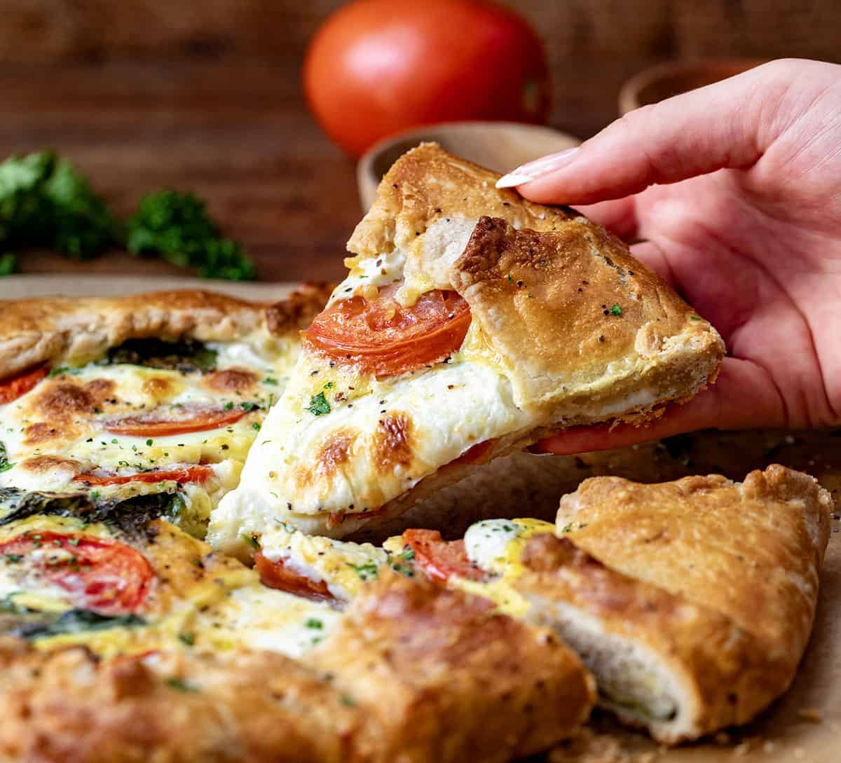 Hand picking up a piece of Caprese Galette.