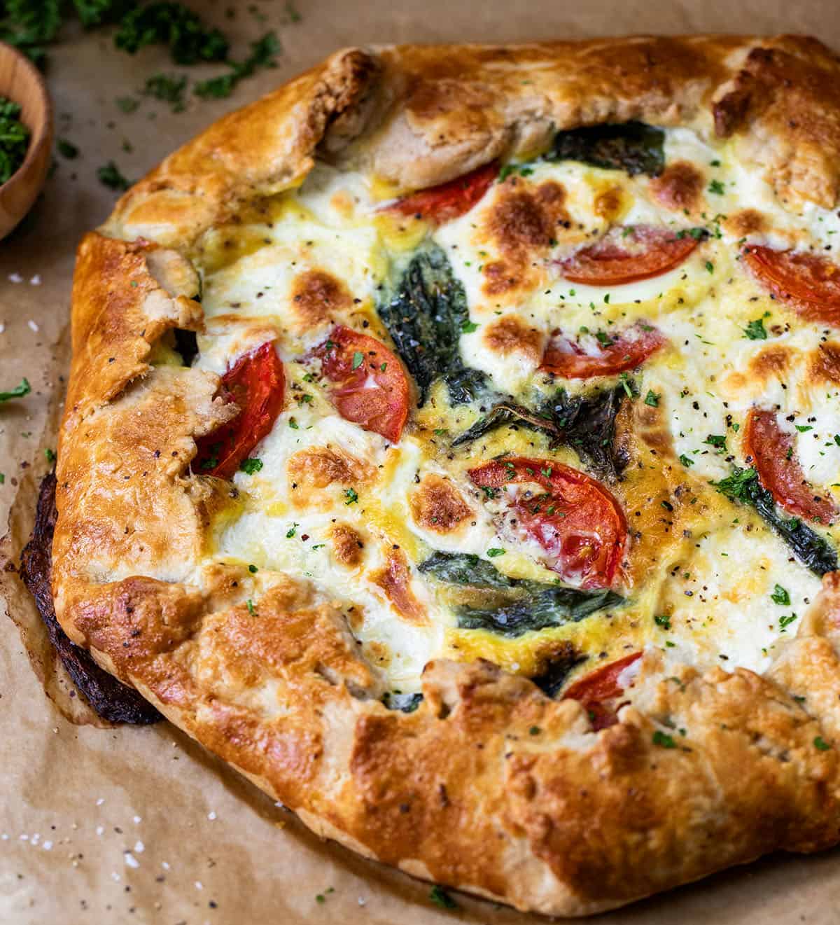 Close up of Caprese Galette on brown parchment paper.