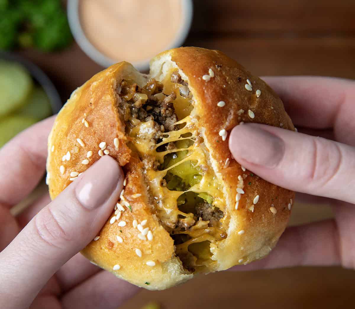 Hand tearing a Cheeseburger Bombs in half showing the inside.