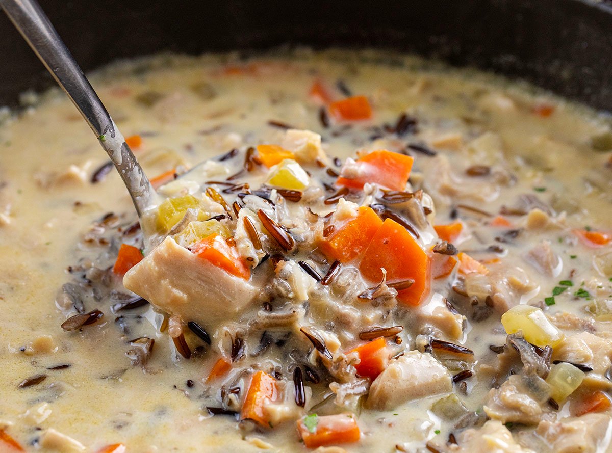 Using a ladle to scoop Chicken Wild Rice Soup from pot.