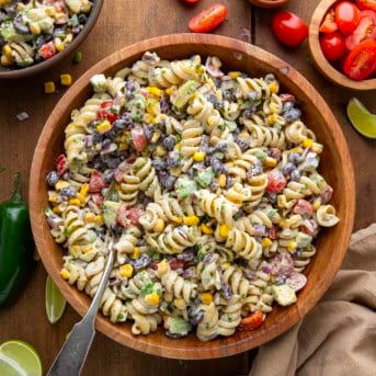 Bowl of Chipotle Lime Pasta Salad with a spoon in it on a wooden table from overhead.