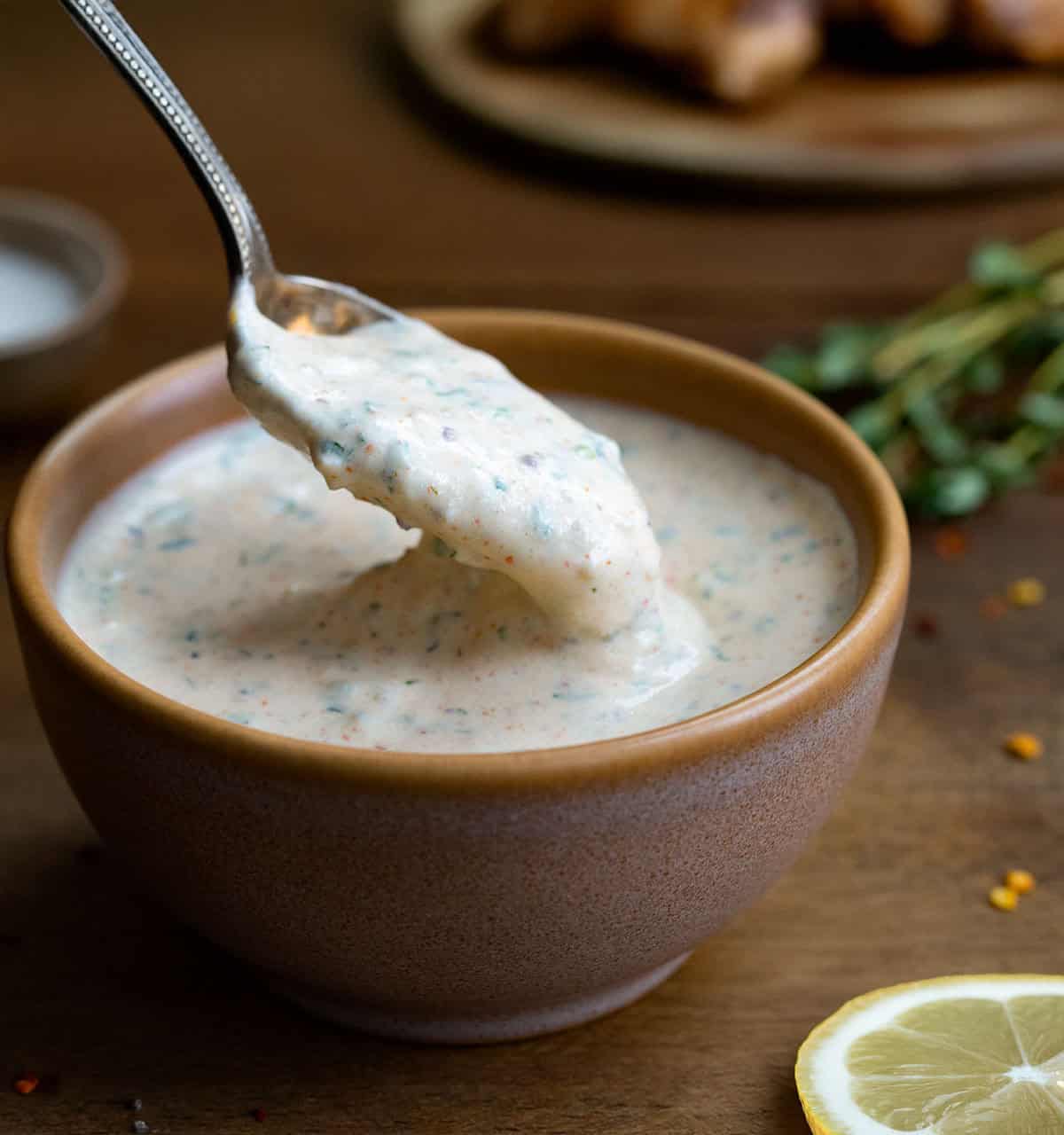 Dipping a spoon into a bowl of Cowboy Butter Ranch Dressing.