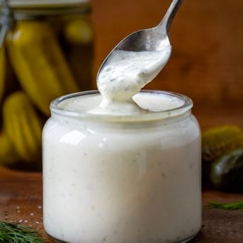 Spoon dipped into Dill Pickle Ranch on a wooden table.