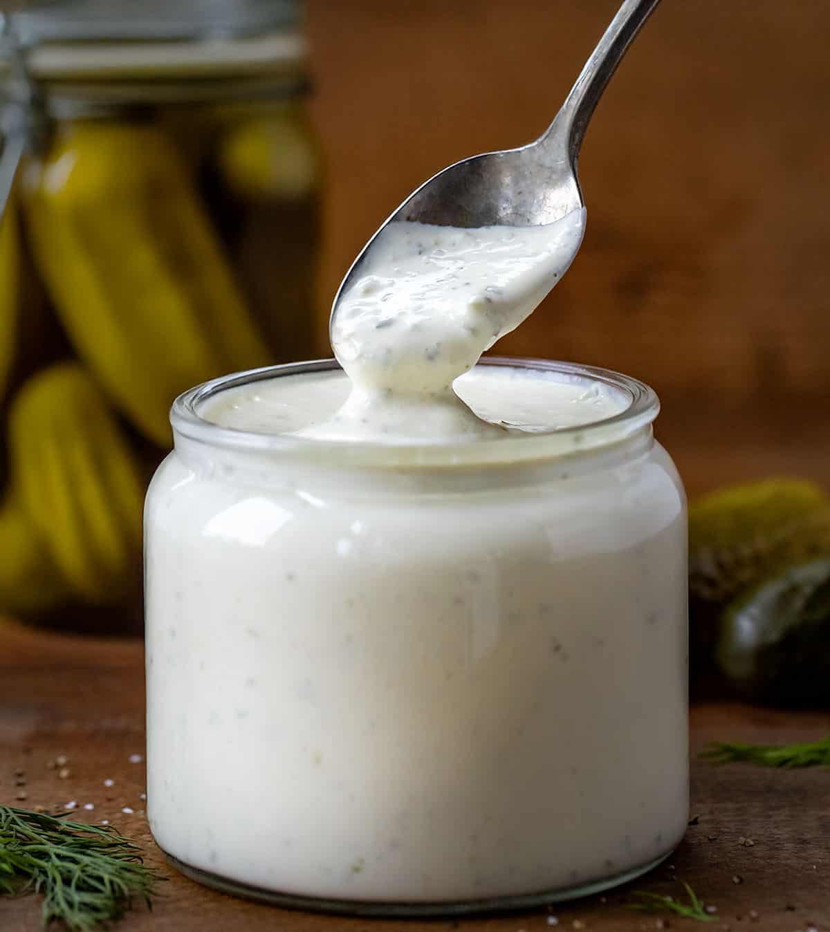 Spoon dipped into Dill Pickle Ranch on a wooden table. 