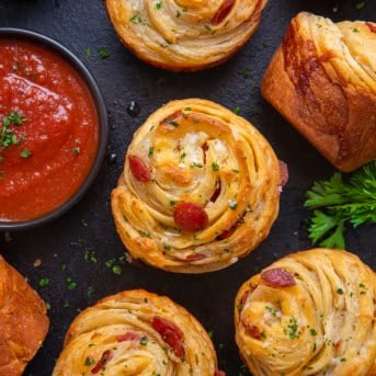 Pizza Cruffins laid out on a counter with pizza sauce.