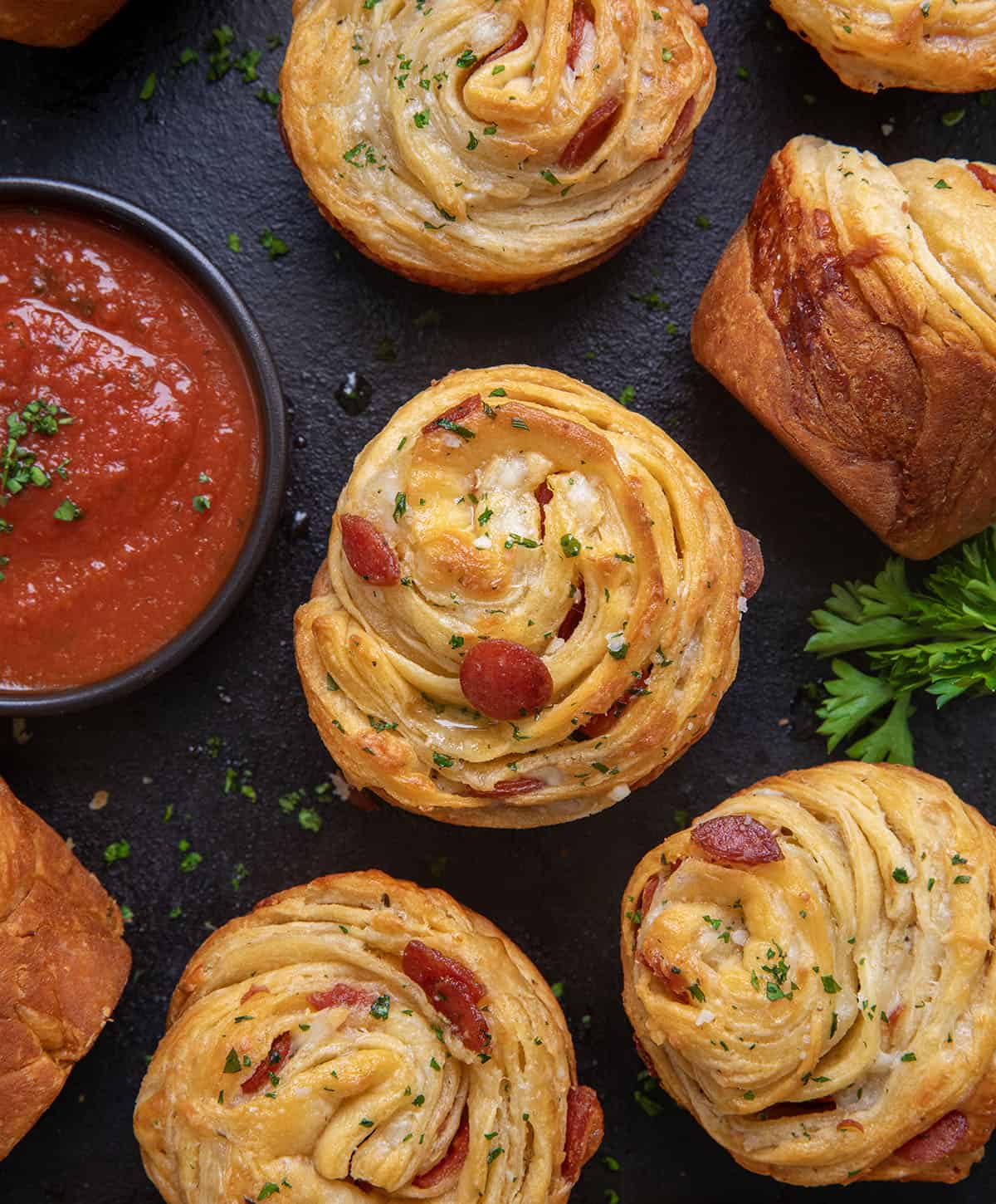 Pizza Cruffins laid out on a counter with pizza sauce. 