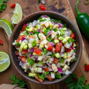 Bowl of Avocado Shrimp Ceviche on a wooden table with limes from overhead.