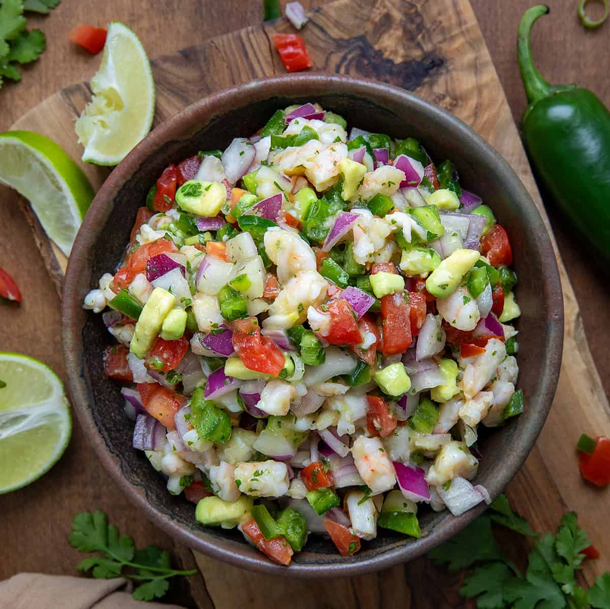 Bowl of Avocado Shrimp Ceviche on a wooden table with limes from overhead.