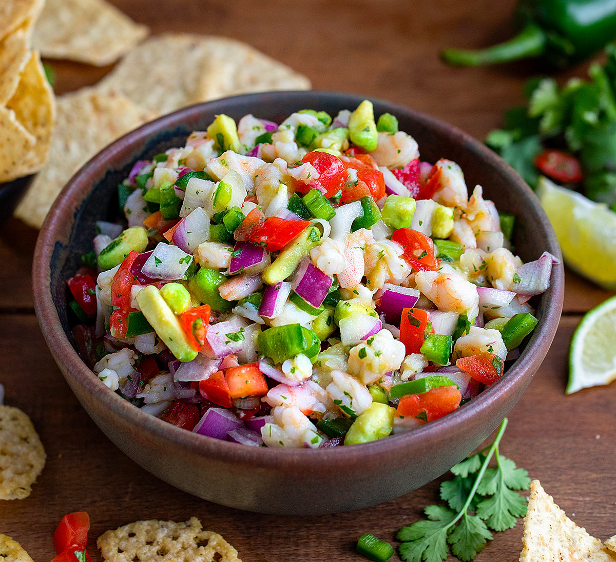 Bowl of Avocado Shrimp Ceviche on a wooden table with chips and cilantro.