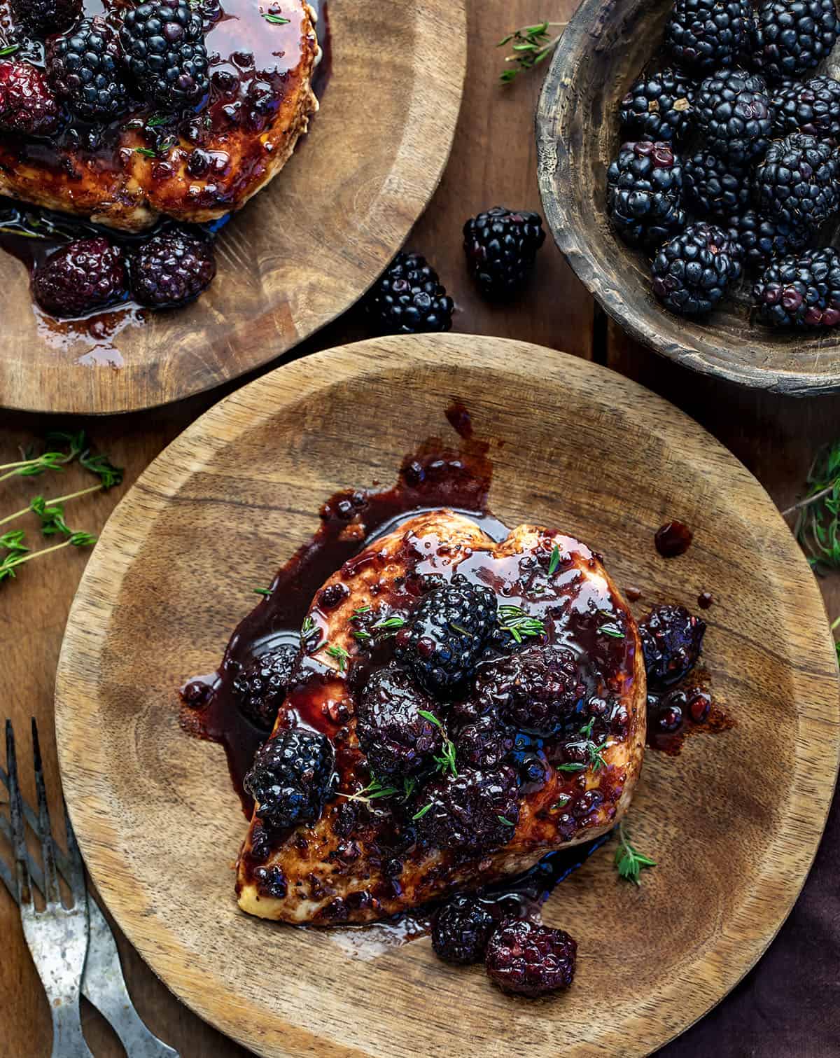 Plates of Bourbon Blackberry Chicken on a wooden table from overhead.