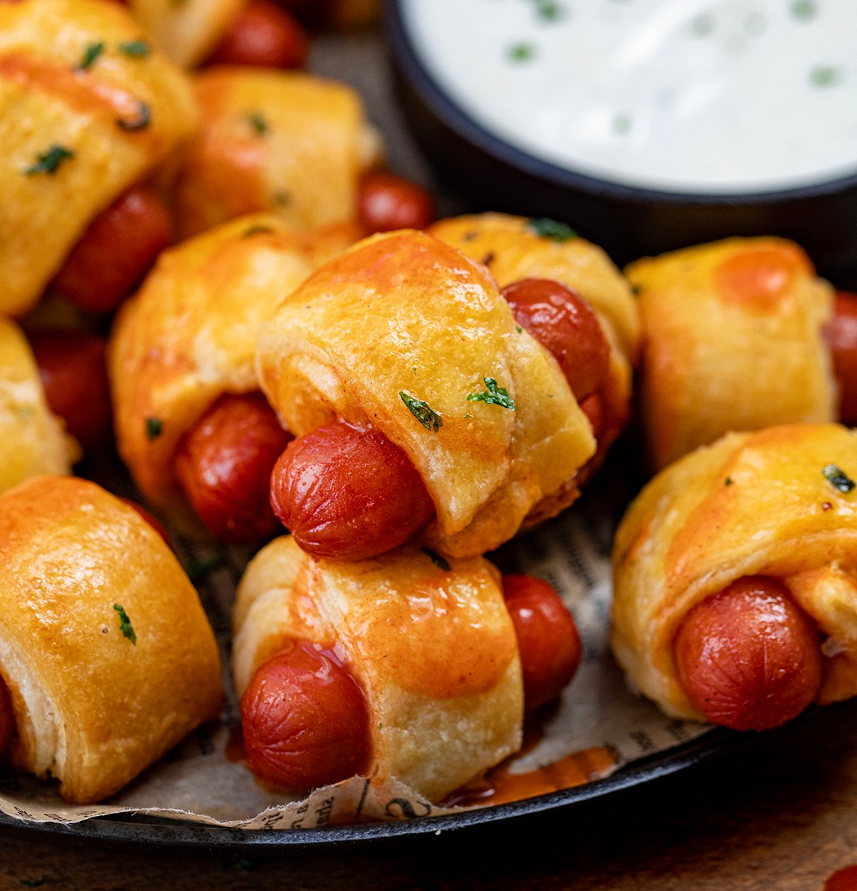 Buffalo Ranch Pigs In A Blanket very close up with ranch dressing in the background.