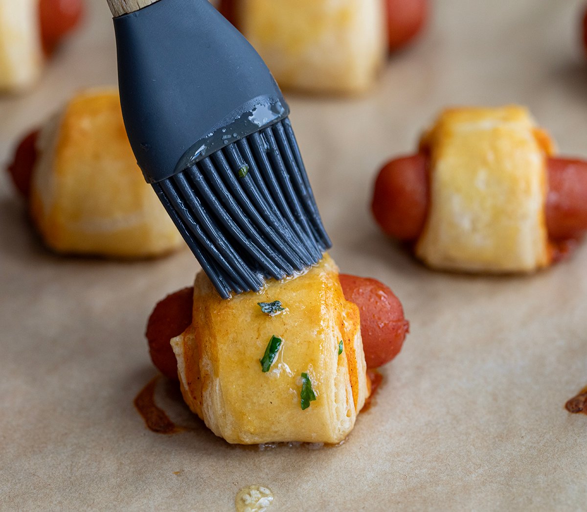 Brushing a butter blend over Buffalo Ranch Pigs In A Blanket.