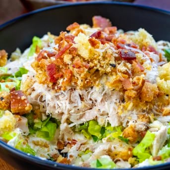 CLose up of a bowl of Chicken Caesar Salad Dip with some of it removed.